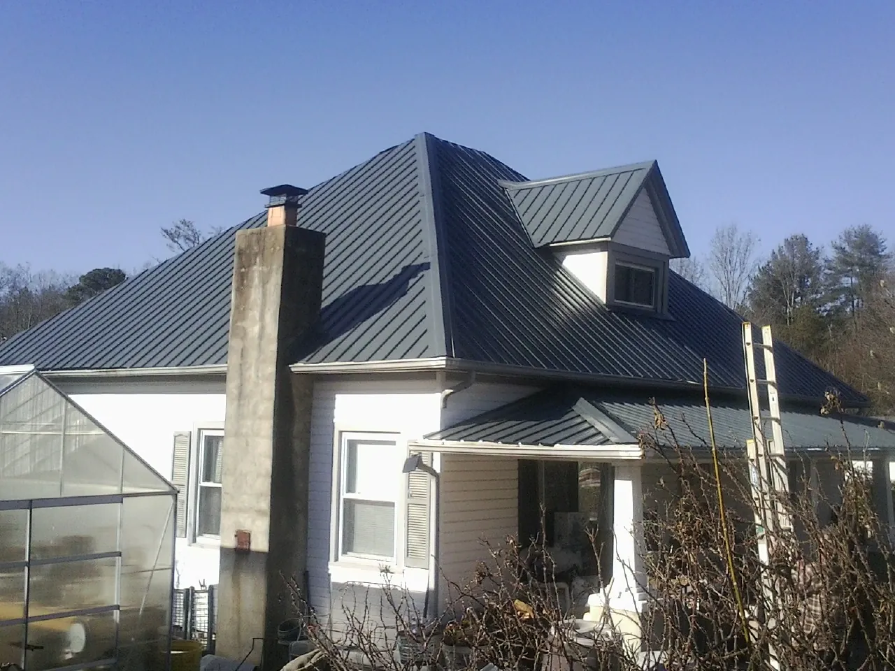 Dark blue standing seam metal roof on a white farmhouse with dormer — Slate & Tile Roof Repair by Roofing Brothers in Thiells