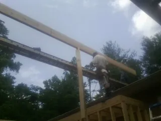 Carpenter setting a ridge beam over a new addition frame — Ice Dam Removal by Roofing Brothers in Thiells