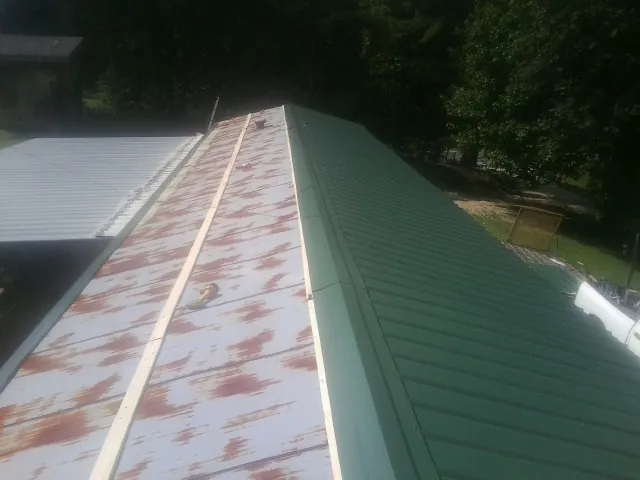 Old rusted panels beside newly installed green metal roofing — Wind Damage Roof Repair by Roofing Brothers in Thiells