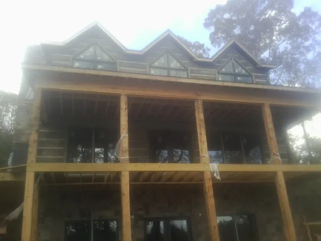 Dormers and porch framing on a large log home under construction — Roof Coating work by our crew in Thiells