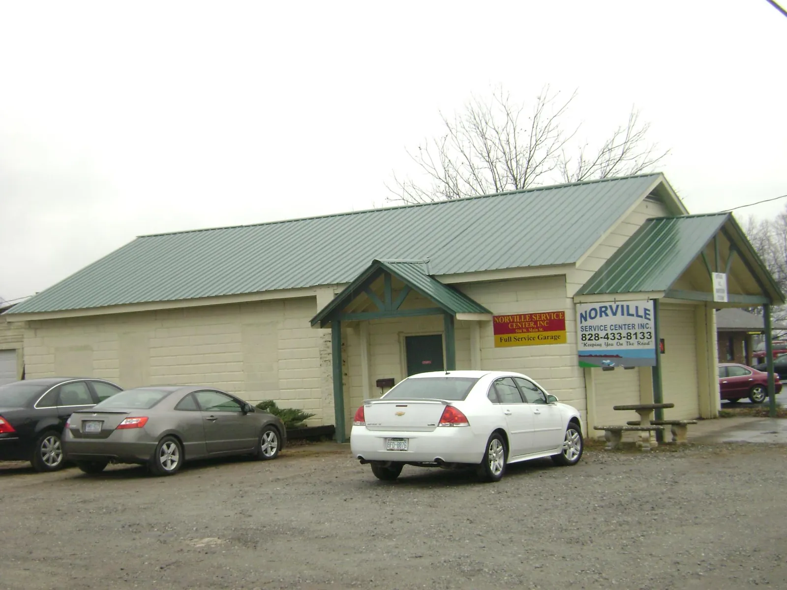 Green metal roof on a service garage with a covered entry in Thiells