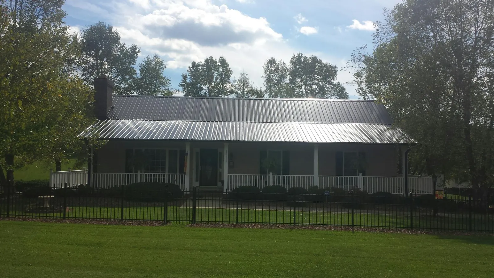 Gray metal roof on a brick ranch with a full width front porch — Gutter Guard Installation work by our crew in Thiells
