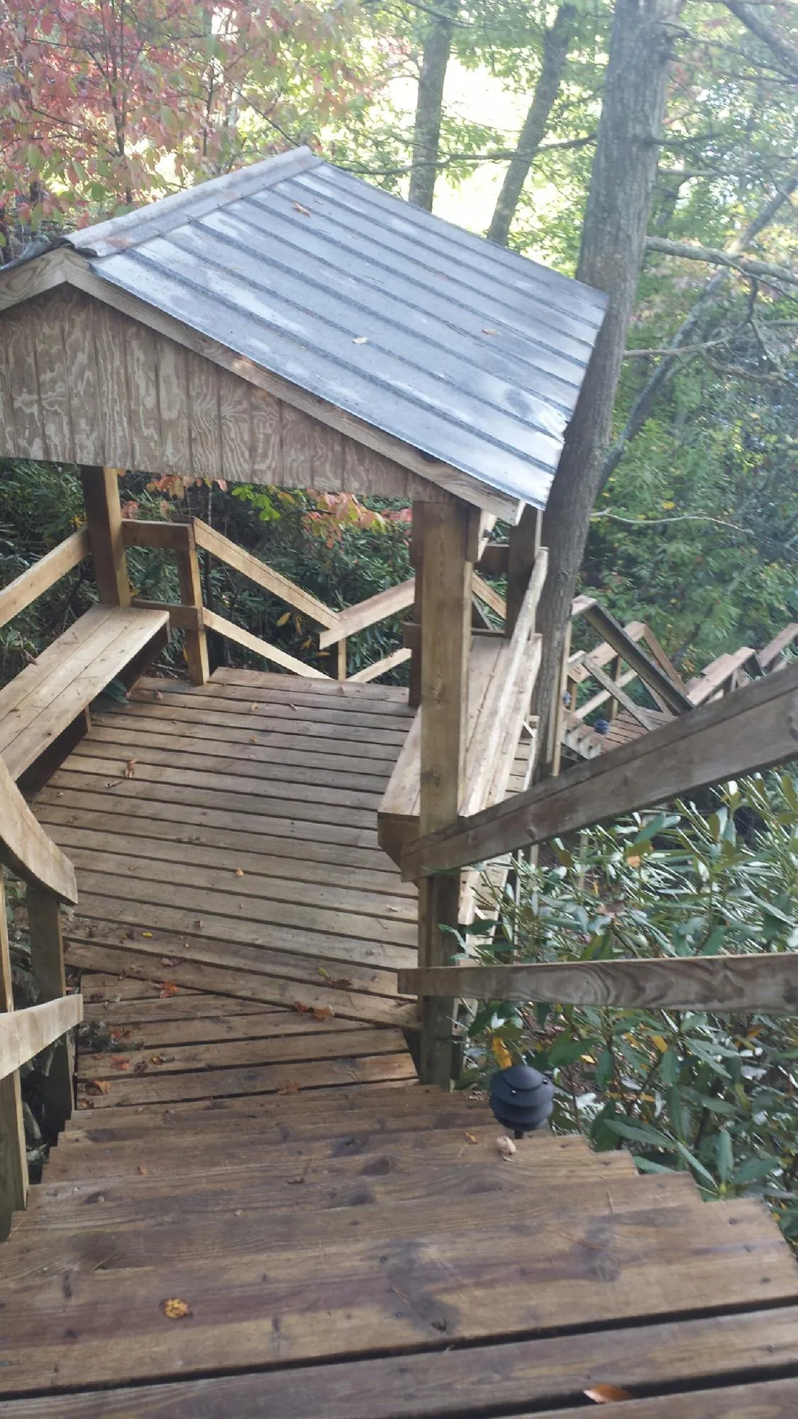 Metal roofed shelter over wooden steps on a wooded walkway — Skylight Repair & Installation work by our crew in Thiells