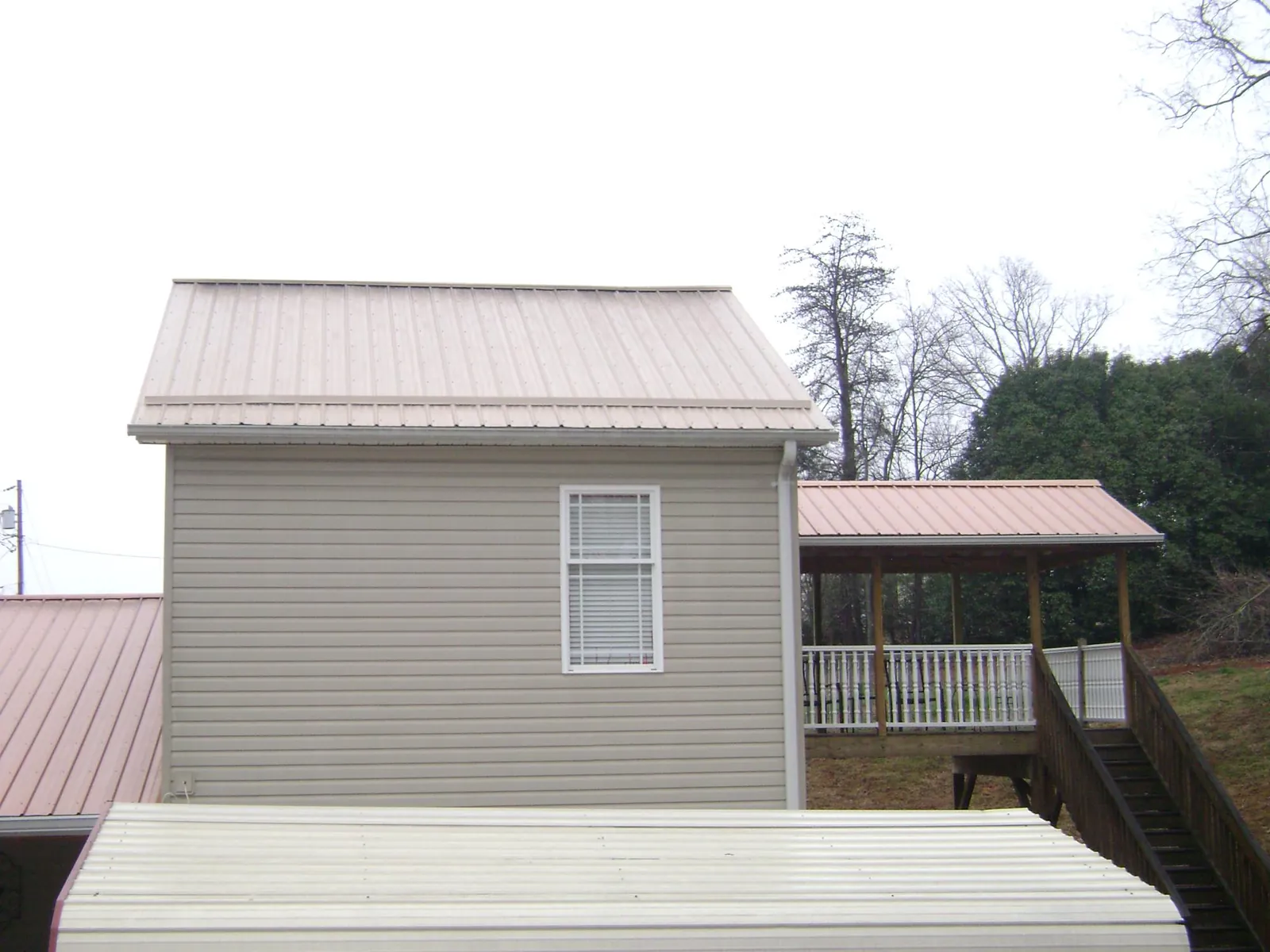 Tan metal roofs on a two story addition and attached porch, from a Roof Replacement job in Thiells