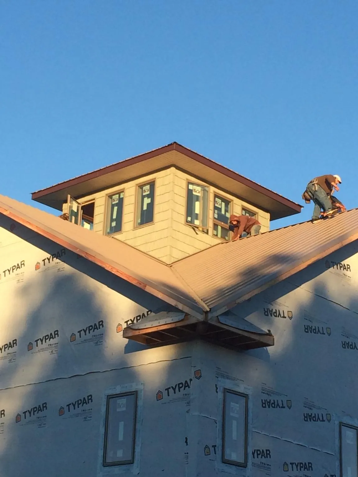 Roofers working around a rooftop cupola on a new metal roof at sunset — Roof Waterproofing in Thiells by Roofing Brothers